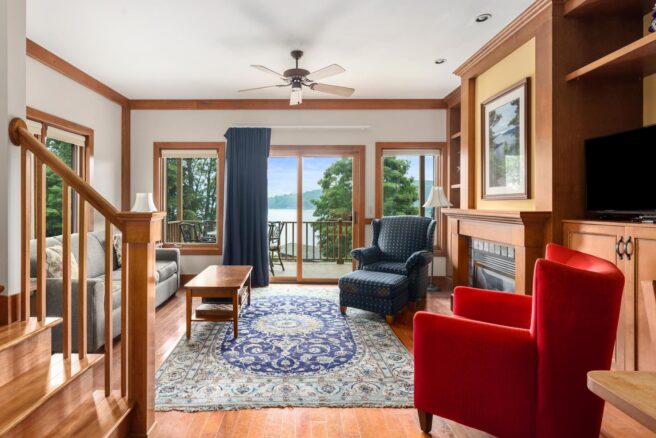 A cozy living room with a fireplace and a picturesque view of the lake at Erlowest, one of Lake George's finest hotels.