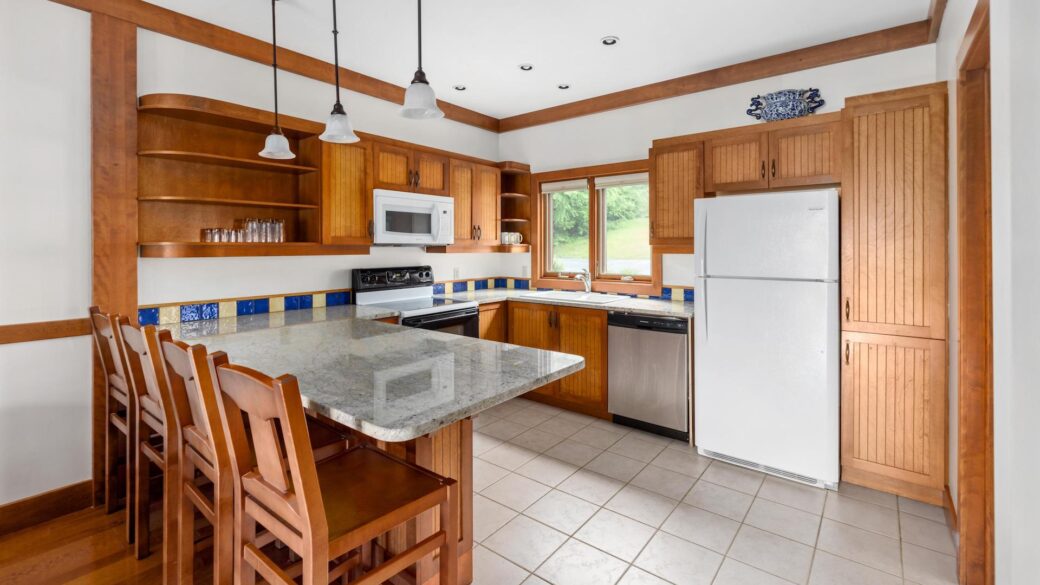 A Lake George lodging with a kitchen featuring wooden cabinets and counter tops.