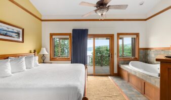 A luxurious hotel with a spacious bedroom featuring a king-sized bed and a refreshing jacuzzi tub, perfect for an unforgettable Lake George vacation.