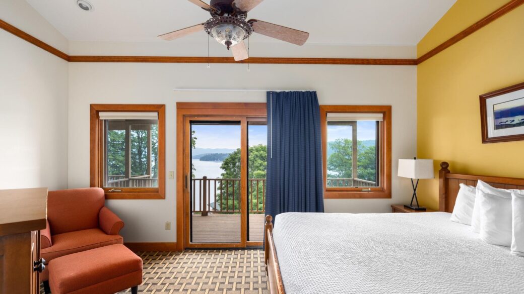 Lake George resort with a bedroom featuring a bed and a balcony overlooking the lake.