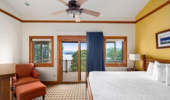 Lake George resort with a bedroom featuring a bed and a balcony overlooking the lake.