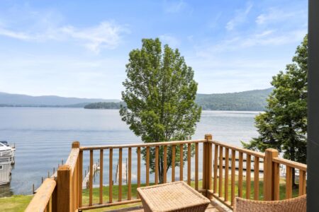 A Lake George hotel offering a scenic deck with wooden table and chairs.