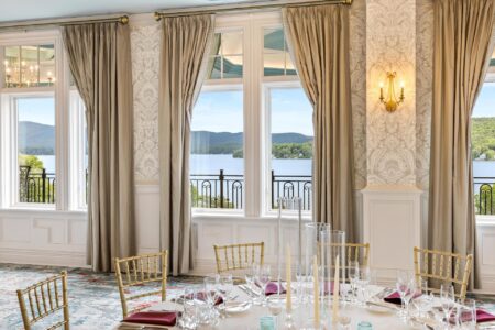 Set dining table and chairs in front of windows showing a lush lake view