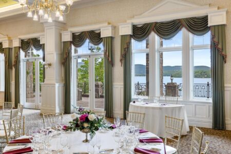 A formal dining room with large windows offering picturesque views of Lake George.