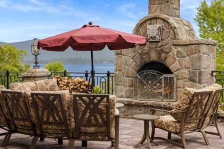 Lake George lodging with a patio featuring a stone fireplace and patio furniture.