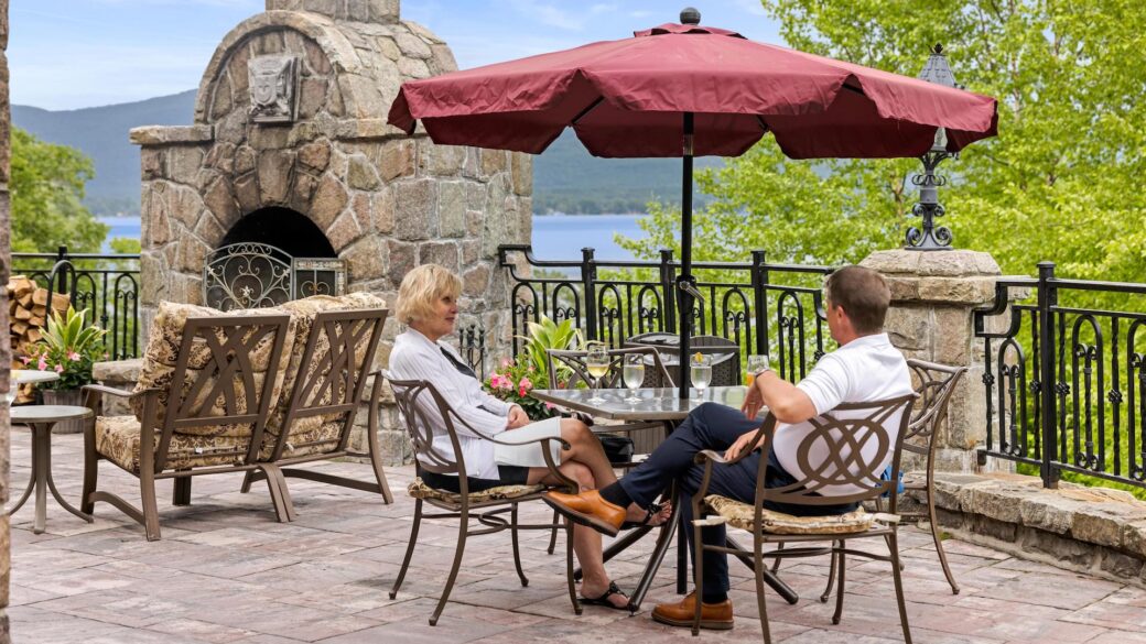 A couple enjoys a romantic meal on a lakefront patio at a Lake George resort.