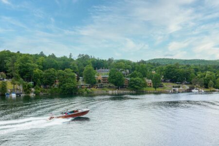 A boat is traveling down Lake George in front of the Erlowest Lake George resort.