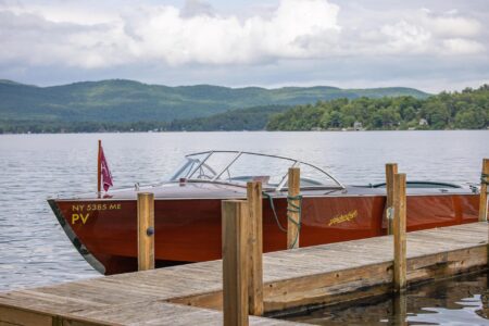 A wooden boat docked at a Lake George dock on a lake
