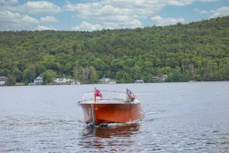Miss Erlowest, The Erlowest's vintage wooden Hacker-Craft boat sails across Lake George against a picturesque backdrop of trees