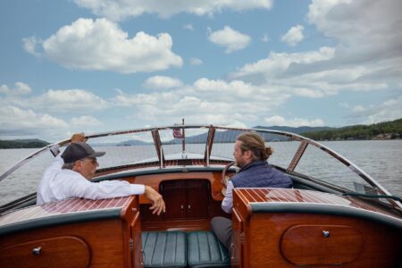 Two men enjoying their Lake George vacation by sitting in the back of a boat on the picturesque lake.