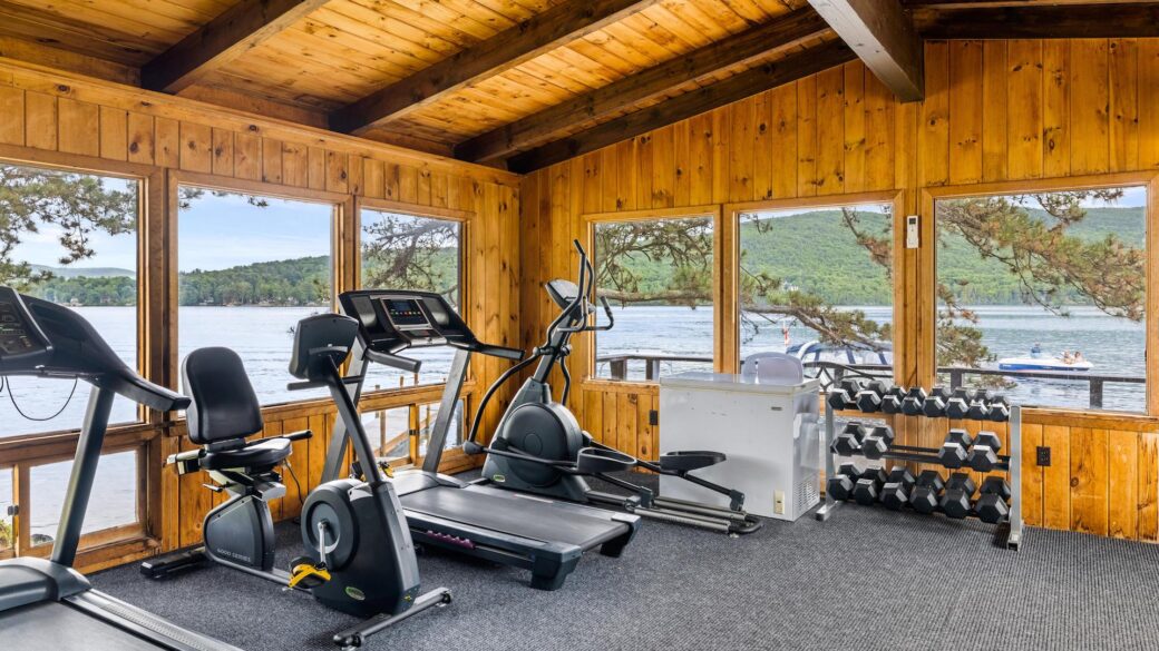 A Lake George resort with a gym room featuring tread machines and a view of the lake.