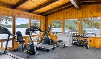 A Lake George resort with a gym room featuring tread machines and a view of the lake.