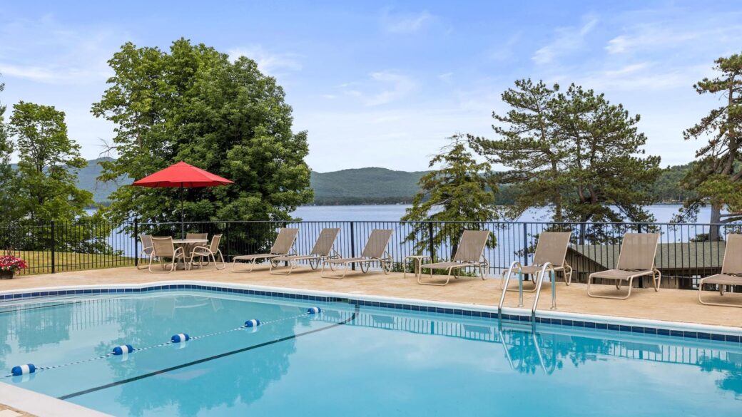Lake George lodging with a swimming pool and lounge chairs overlooking the lake.