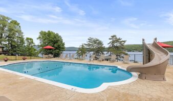 Lake George hotel with pool and chairs near lake.