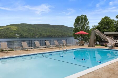 A lakefront resort featuring a swimming pool with a slide and chairs.