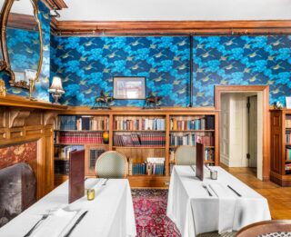 A dining room at Erlowest with blue wallpaper and bookshelves.