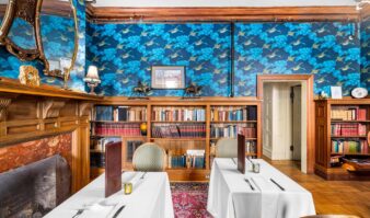 A dining room at Erlowest with blue wallpaper and bookshelves.