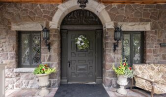 Lake George lodging with a stone front door adorned by a bench and potted plants.