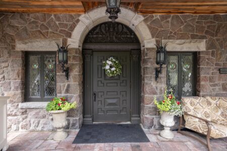 Lake George lodging with a stone front door adorned by a bench and potted plants.