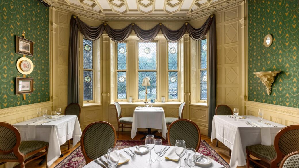 A Lake George vacation dining room at Erlowest with green walls and white tablecloths.