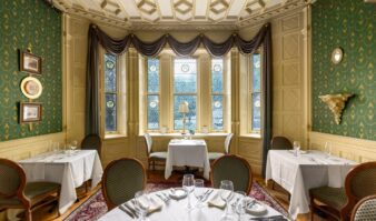 A Lake George vacation dining room at Erlowest with green walls and white tablecloths.