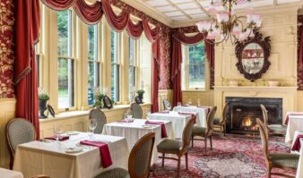 An Erlowest hotel with an ornate dining room featuring a fireplace, perfect for a Lake George vacation.