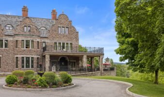 A grand stone mansion nestled in the picturesque Lake George, offering a spacious driveway for an unforgettable Lake George vacation experience.