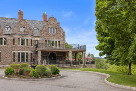 A grand stone mansion nestled in the picturesque Lake George, offering a spacious driveway for an unforgettable Lake George vacation experience.