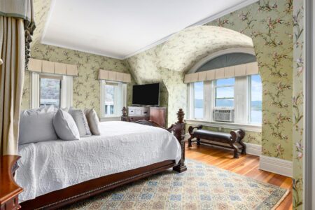 A bedroom with floral wallpaper and a view of the ocean at Lake George resort.