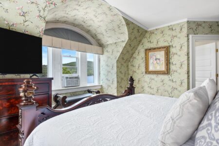 A Lake George resort bedroom with floral wallpaper and a TV at Erlowest, one of the best hotels in the area.