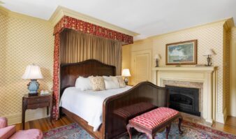 Lake George lodging featuring a bedroom with a large bed and a fireplace.