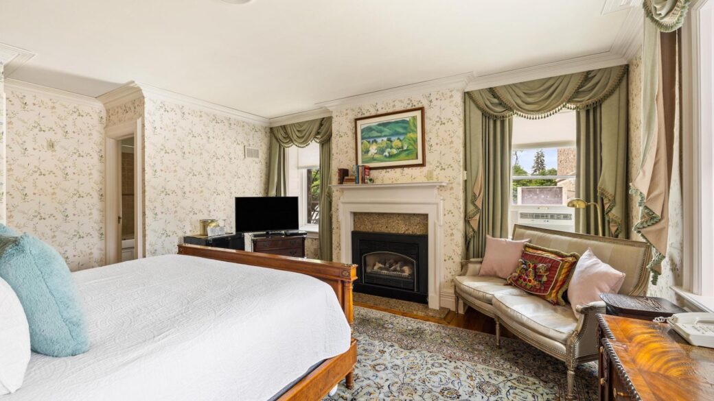 A Lake George hotel room featuring an ornate bed and a fireplace for the perfect Lake George vacation.