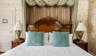 A pristine canopy bed sits in a beautifully decorated room at Erlowest, a luxury Lake George Hotel.