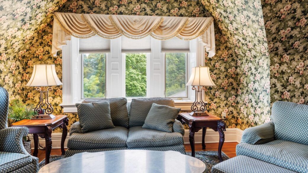 A living room with floral wallpaper located in Erlowest, one of the Lake George hotels perfect for a tranquil Lake George vacation.