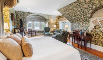 A cozy bedroom with floral wallpaper and a comfortable bed, perfect for Erlowest guests seeking Lake George lodging.