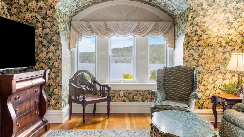 A living room with floral wallpaper and a tv in one of the best hotels in Lake George.