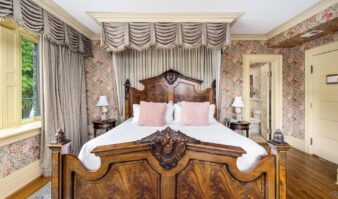 Lake George lodging with an ornate bed and floral wallpaper at Erlowest.