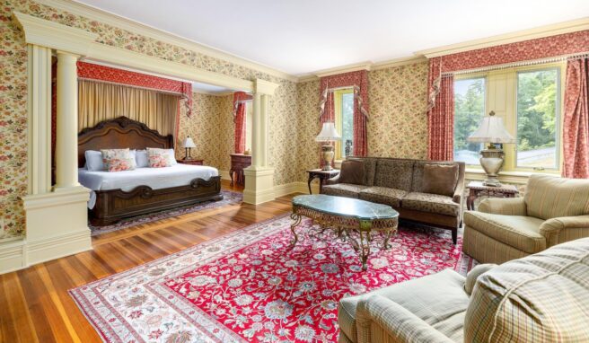 An ornately decorated bedroom at Erlowest, a Lake George lodging, featuring a bed and couch.