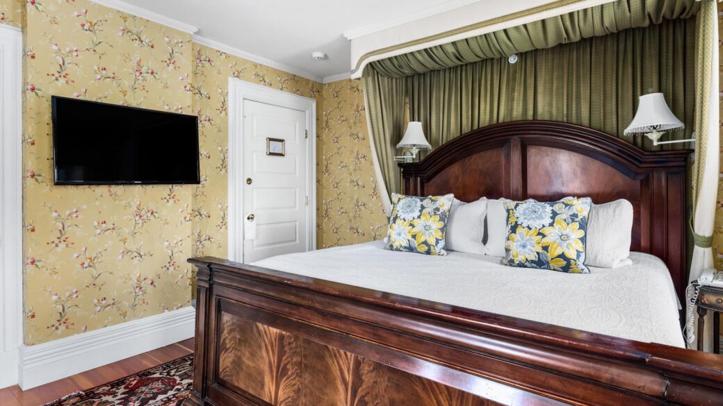 A Lake George hotel room with floral wallpaper and a TV.