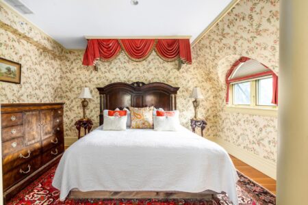 A bedroom with a bed and floral wallpaper in a Lake George resort.