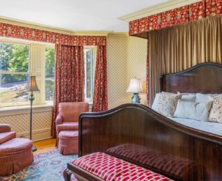A wide view of a hotel room with a large bed, chair, and window