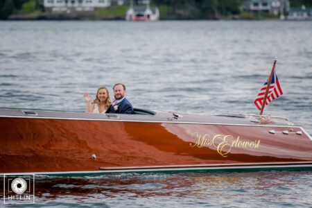 A newlywed couple embracing on a romantic wooden boat ride at a Lake George resort.