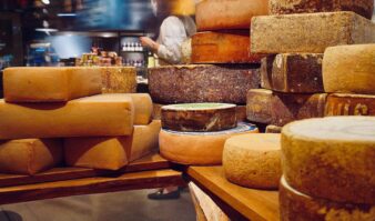 Many cheeses are stacked on a wooden table at Erlowest, one of the best hotels in Lake George for a vacation.