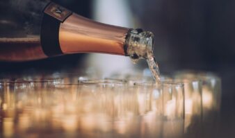 A bottle of champagne is being poured into glasses.