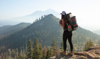 A woman with a backpack standing on top of a mountain.