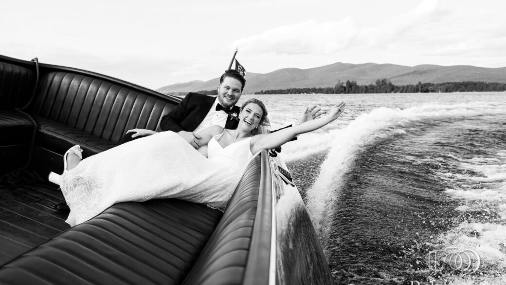 A bride and groom riding in the back of a boat.
