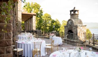 A wedding reception set up on a stone patio overlooking a lake.