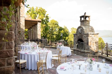 A wedding reception set up on a stone patio overlooking a lake.