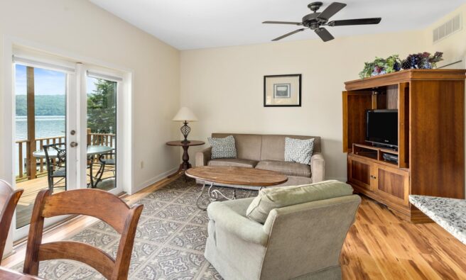 A living room with a balcony overlooking a lake.