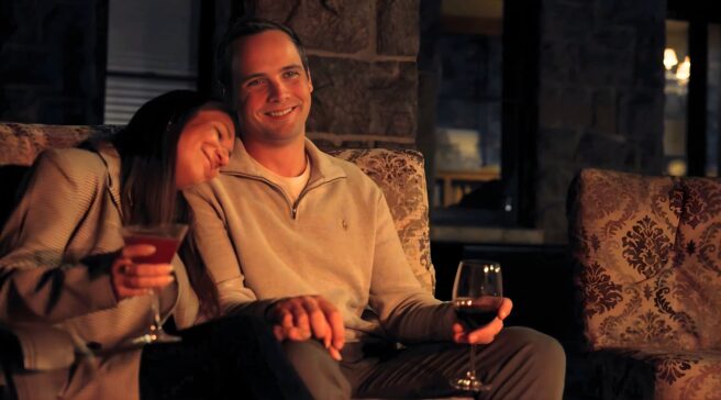 Couple enjoying wine by an outdoor fireplace, seated on couches at The Inn at Erlowest